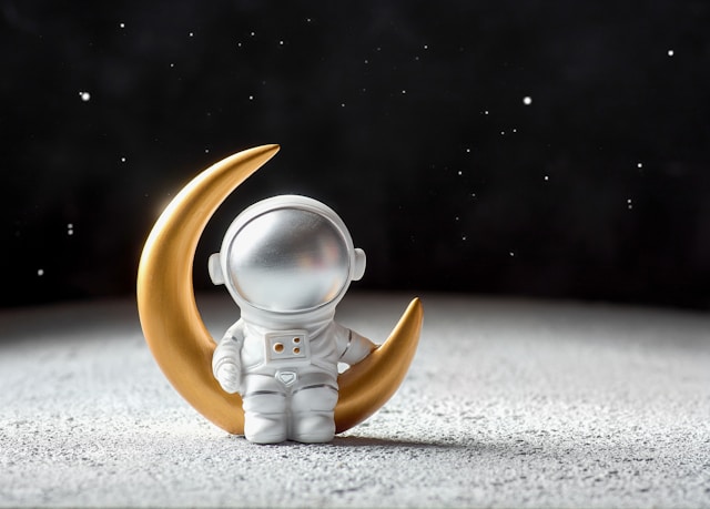 A tiny toy astronaut, sitting on a yellow toy moon